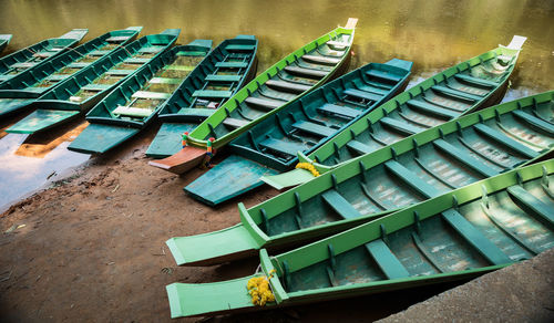 High angle view of green rowboats moored in row on lakeshore