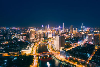 High angle view of illuminated city buildings against clear sky at night