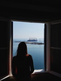 Rear view of woman looking through window