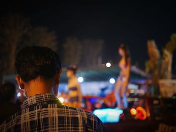 Rear view of man at music concert at night