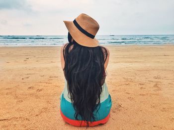 Rear view of woman standing on beach against sky