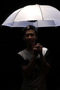 Man holding umbrella against black background