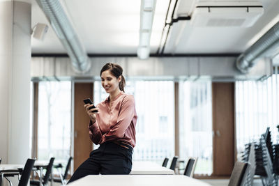 Female entrepreneur using mobile phone at conference table in board room