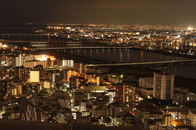 Illuminated modern buildings in city against sky at night