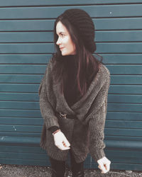 Woman looking away while standing against wall