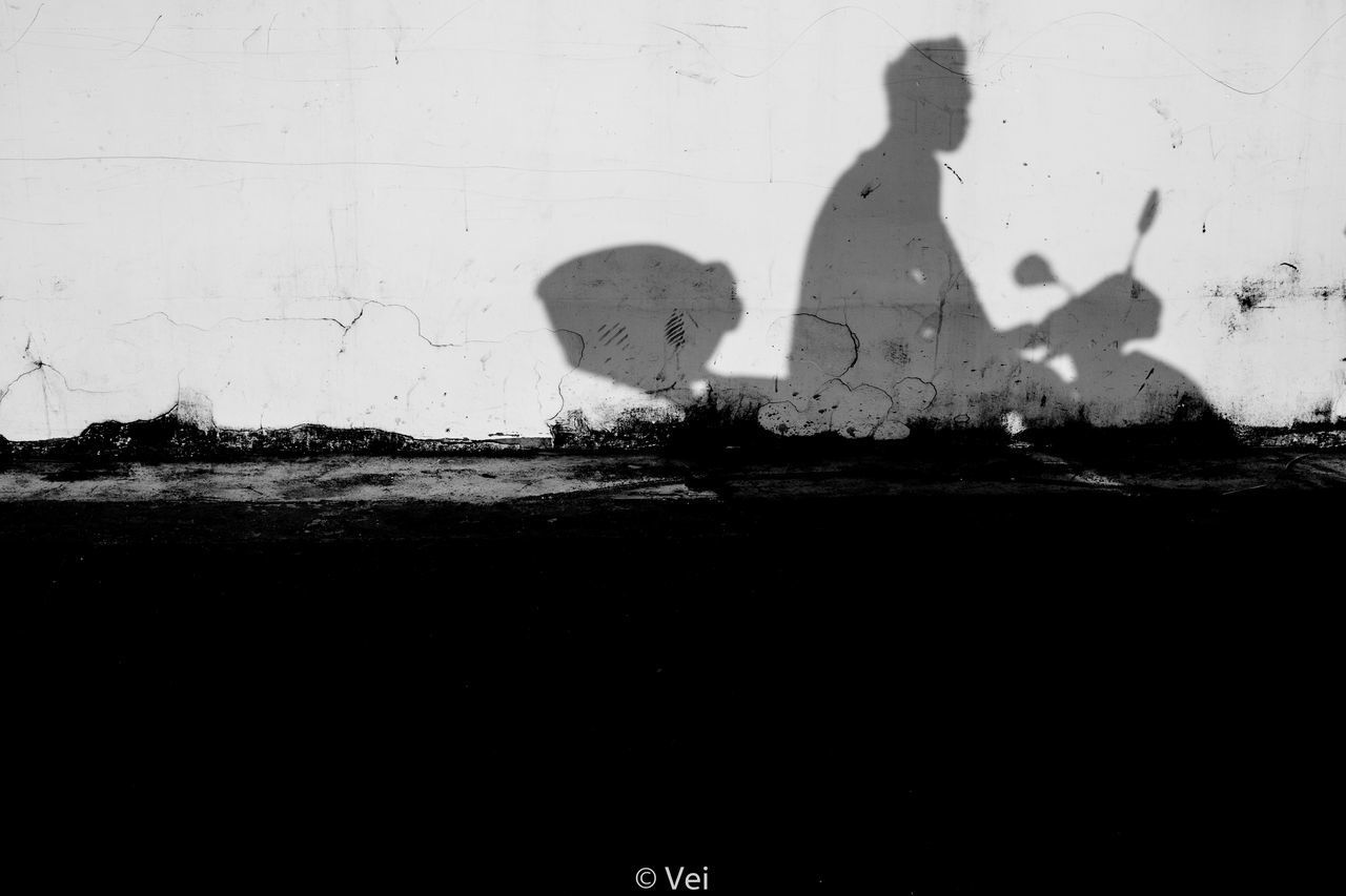 SHADOW OF MAN ON WOMAN ROAD