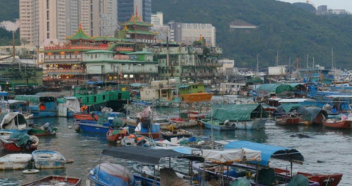 High angle view of boats moored at harbor by buildings in city