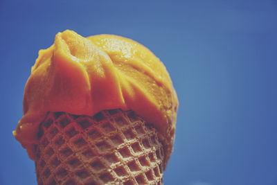 Low angle view of ice cream cone against clear blue sky