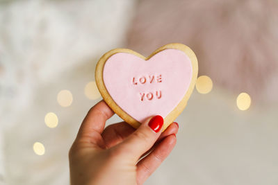 Valentine's day postcard.a woman's hand holds a cookie with the inscription love you