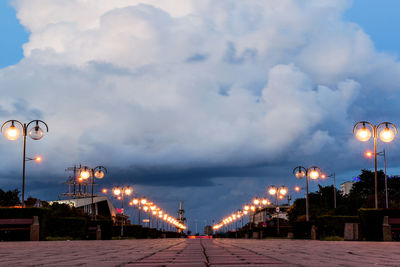 Illuminated street lights against sky at night