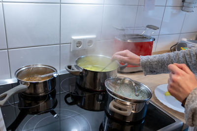 Woman cooking on cooker in the kitchen with hot steam and pots on a ceran stove to cook