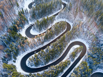 Winding road through the forest, from high mountain pass, in winter time