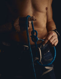Midsection of shirtless man holding rope