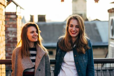 Portrait of smiling young friends standing against buildings