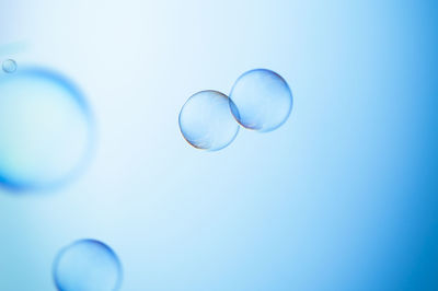 Low angle view of bubbles against blue background