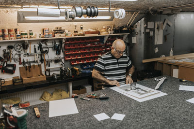 Senior craftsman making frame while standing at workbench