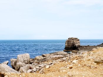 Scenic view of rocks on beach against sky