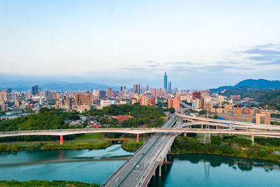 Bridge over river by buildings against sky in city