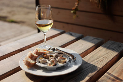 Glass with wine and dish with the snail shells, served on a white classic plate, with various sauces