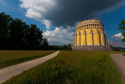 Built structure on field against cloudy sky