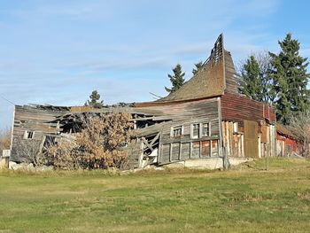 Abandoned house on field against sky