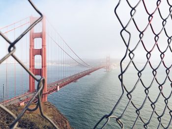 View of suspension bridge through chainlink fence