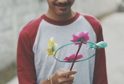 Midsection of young man holding pinwheel toy