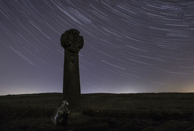 Cross on field against sky at night