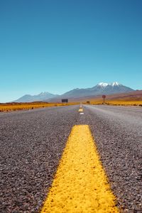 Surface level of road against clear blue sky
