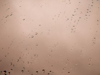 Close-up of waterdrops on glass against the sky