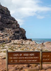 Information sign on rock by sea against sky