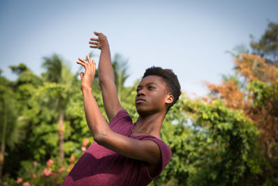 Low angle view of young woman against trees