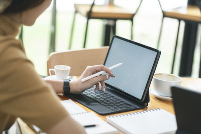 Midsection of woman using laptop on table