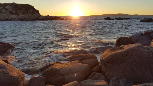 Rocks in sea at sunset