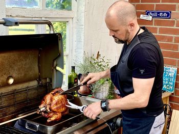 Side view of man preparing food on barbecue