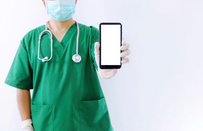 Midsection of man using mobile phone against white background