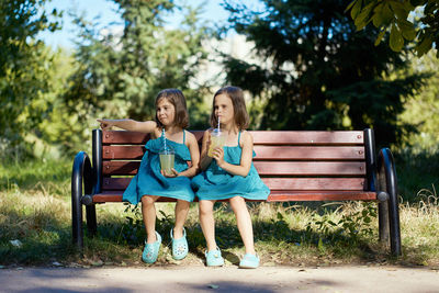 Two little girls drinking lemonade in park