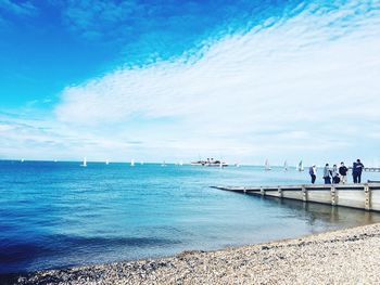 People on beach against blue sky