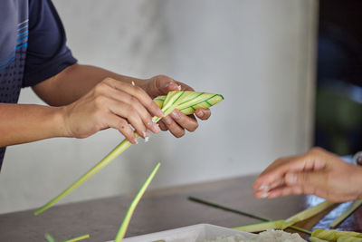 Woman hand wrapping the sticky rice with palm leaf or ketupat palas