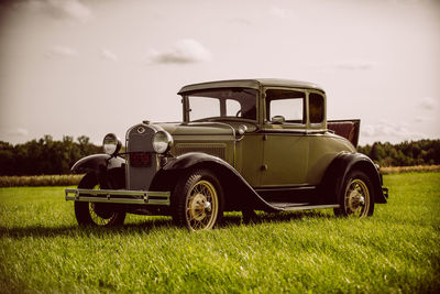 Vintage car on field against sky