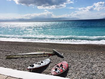 High angle view of surfboards on sand at beach against cloudy sky