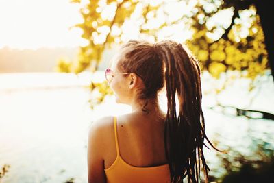 Young woman looking away while standing outdoors