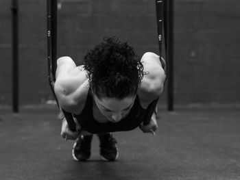 Exercising woman holding gymnast rings in black and white