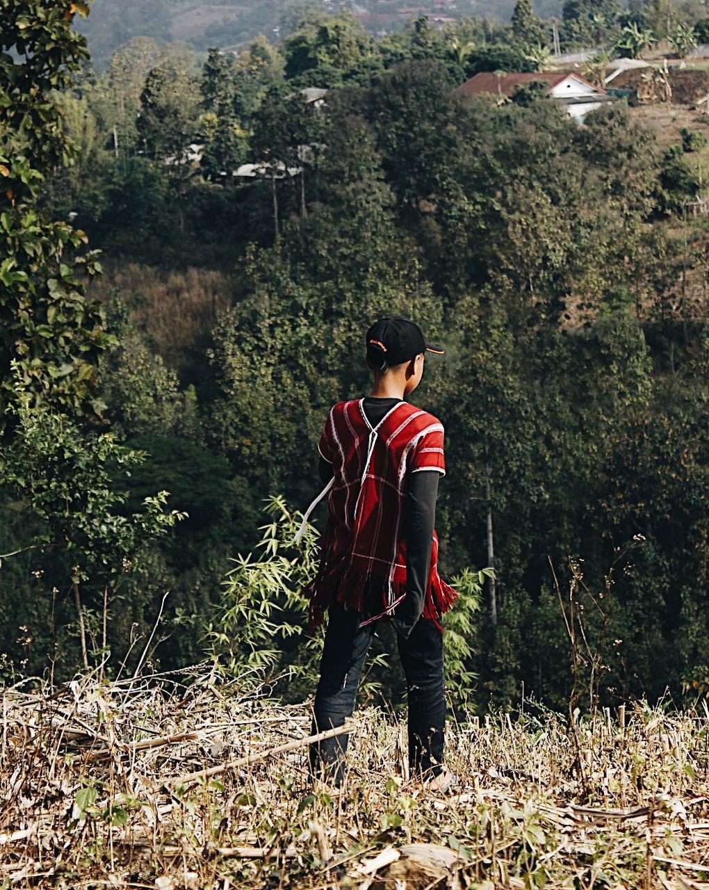 MAN STANDING BY PLANTS ON LAND