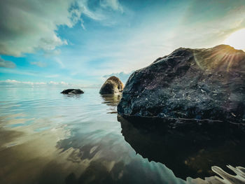 Reflection of rocks in sea against sky