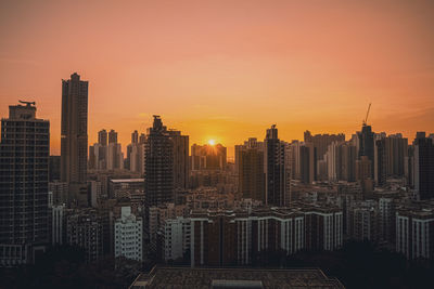 Modern buildings in city against sky during sunset