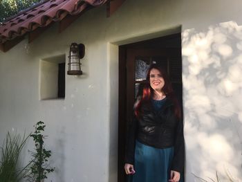 Portrait of smiling young woman standing at entrance