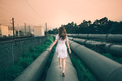 Woman on pipe against sky