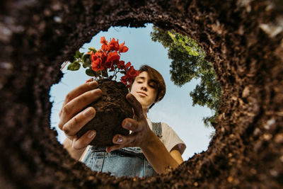 Portrait of happy woman holding flowers on tree trunk