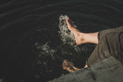 Low section of woman splashing water in sea